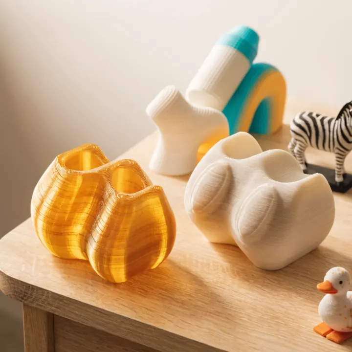 Illustrative 3D printed abstract props, animal figures, duck mascot, and zebra figure on a tabletop.